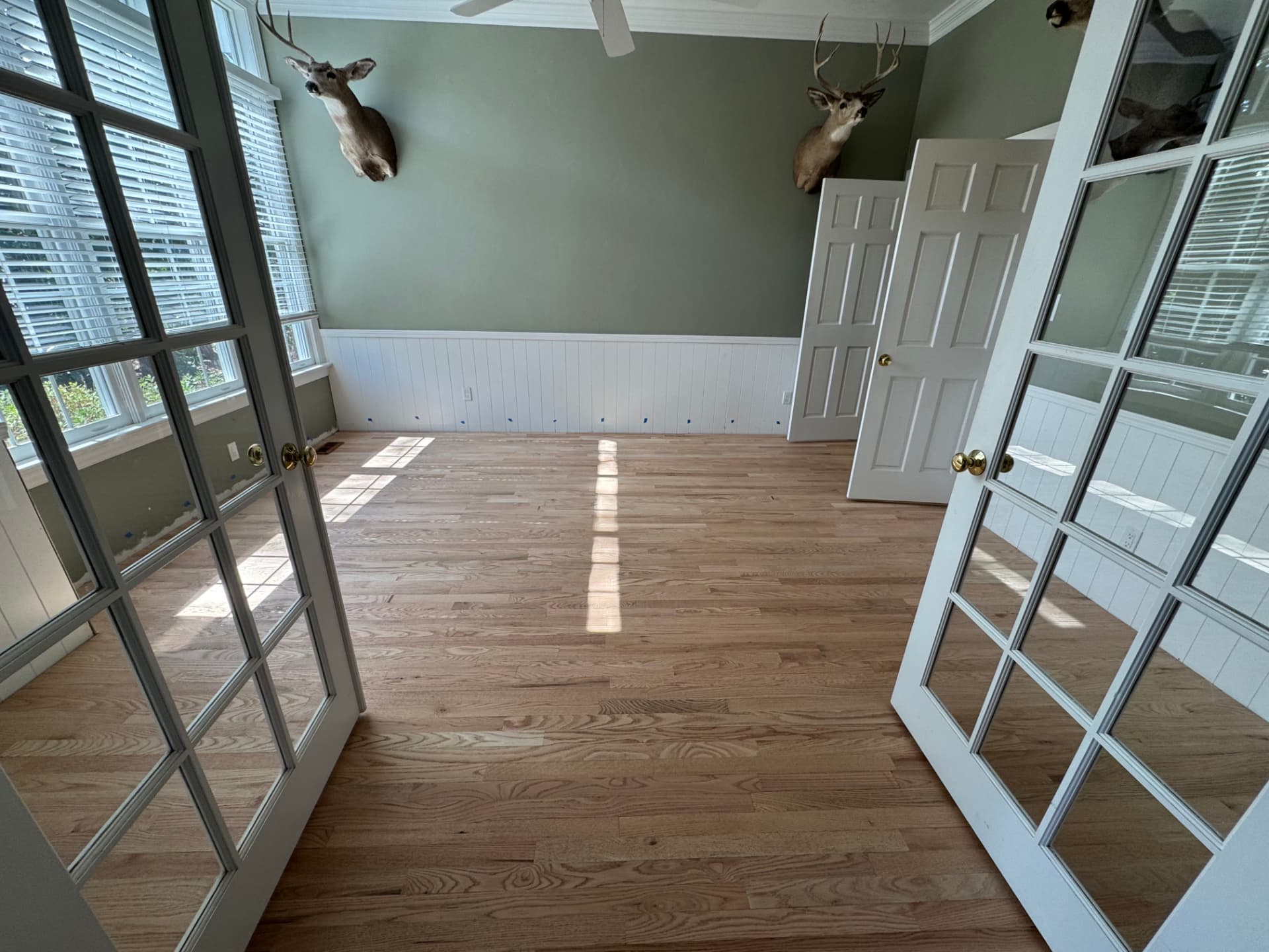 New red oak hardwood flooring installed in a sunlit room with wainscoting
