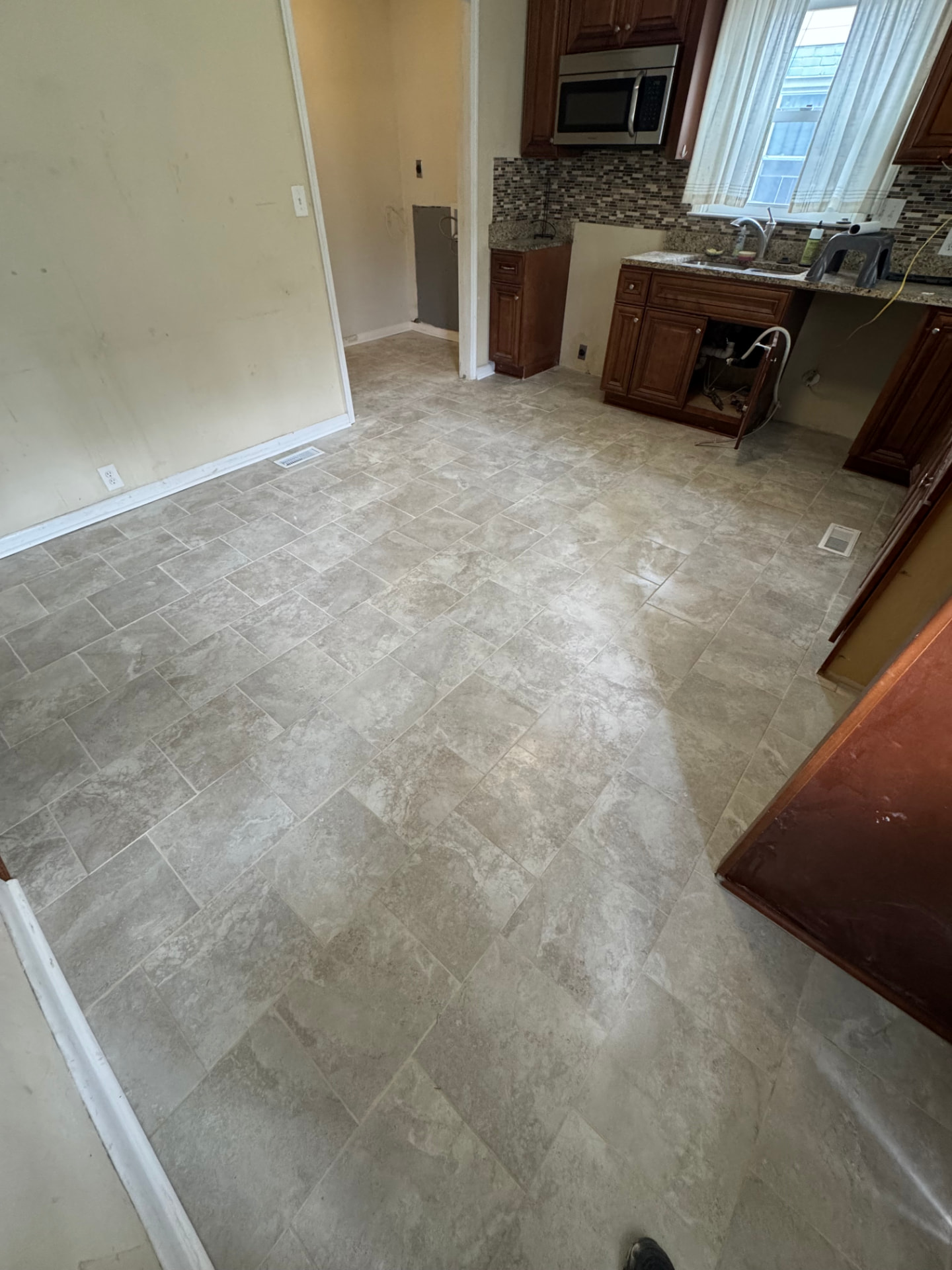 New stone-look tile flooring installed through a kitchen and hallway