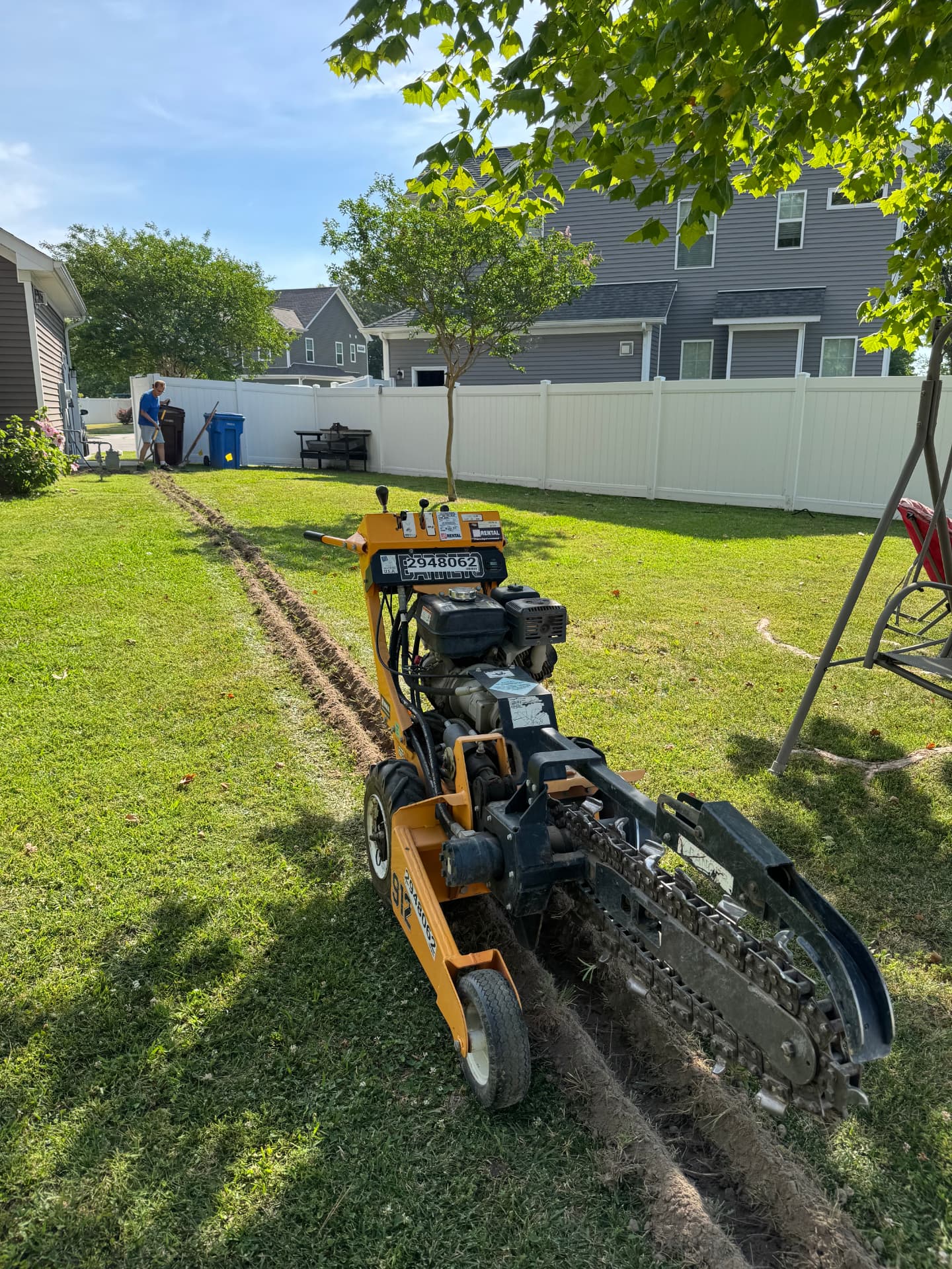 Trencher digging a conduit line across a backyard for underground electrical